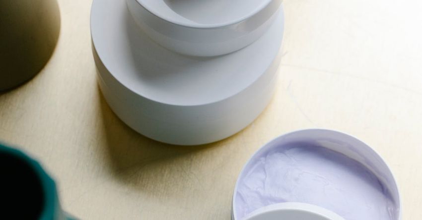 Table Size - From above collection of various skin care products in minimalist white jars stacked on wooden table near vases in daylight