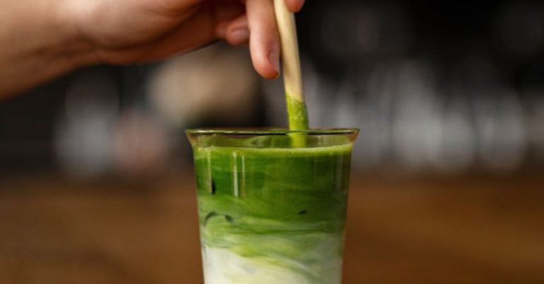 Glass Table - A person holding a wooden stick in a glass of green tea