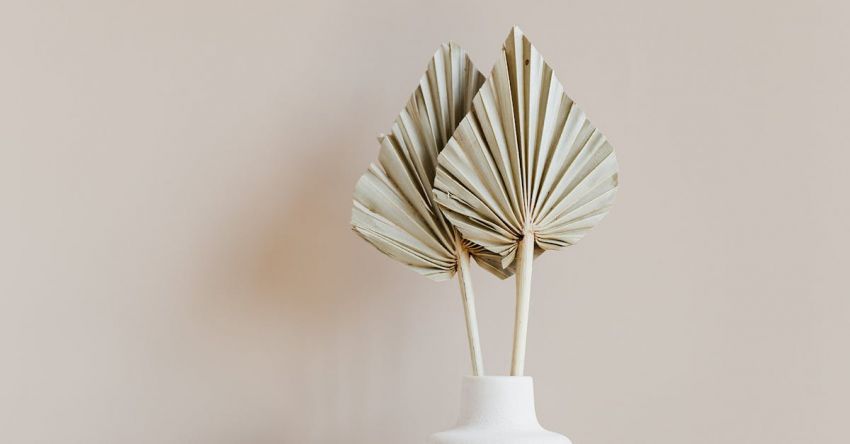 Unique Table - Decorative golden leaves in unique formed white vase placed on marble table against beige background